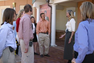 a tour guide with a belt=pack transmitter and a headset and group individuals with receivers and headphones