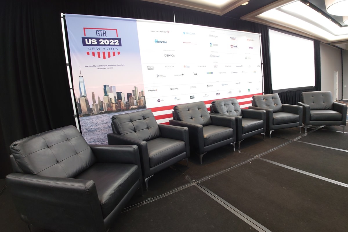 economy backdrop on stage for panel discussion featuring the city of New York on the left and logos on the right