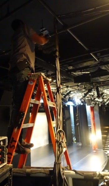 installer on a ladder with the stage as background