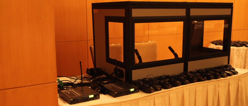 hero image of table top interpreter booth set up on table with receivers layed out in front and RF transmitters on the side.